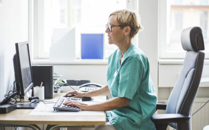 Koncentrerad kvinnlig läkare som sitter vid skrivbord på sjukhus