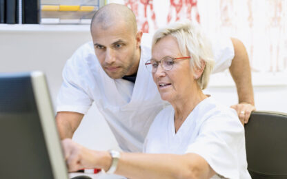 Doctors discussing over computer in office at orthopedic clinic
